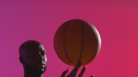 Close-Up-Studio-Shot-Of-Male-Basketball-Player-Spinning-Ball-On-Finger-Against-Pink-Lit-Background-1